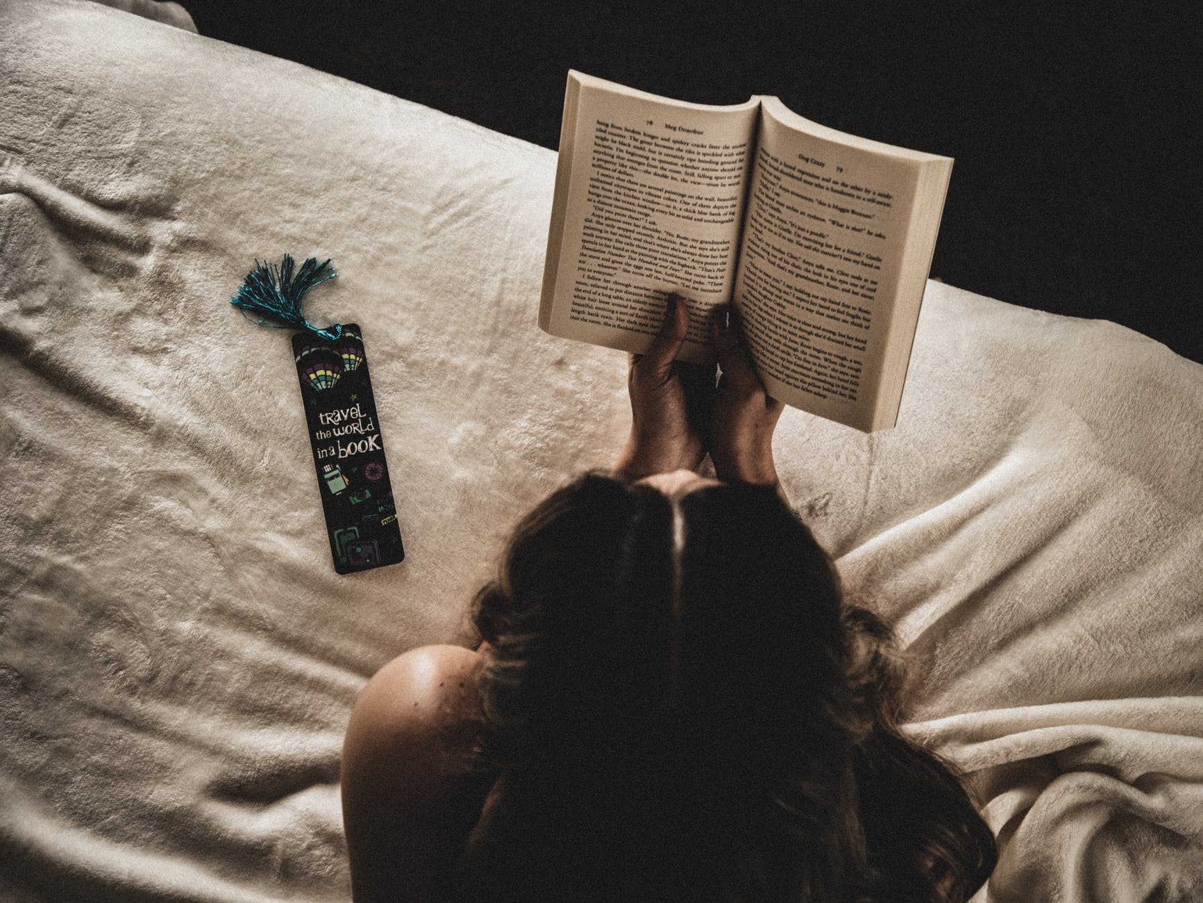 photo of woman reading book on bed